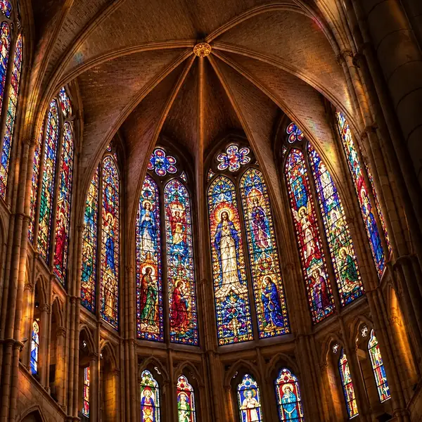 Das Innere einer gotischen Kathedrale mit steinernem Gewölbe und farbenfrohen Buntglasfenstern.